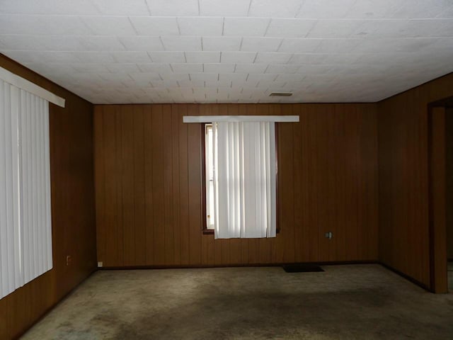 unfurnished room featuring carpet, visible vents, and wooden walls