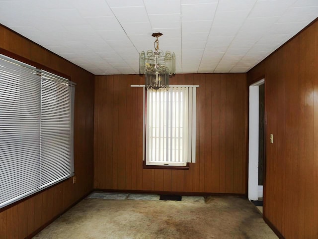 spare room with light colored carpet, wooden walls, and an inviting chandelier