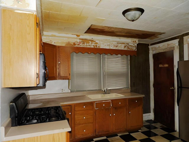 kitchen featuring light countertops, brown cabinetry, a sink, black appliances, and tile patterned floors