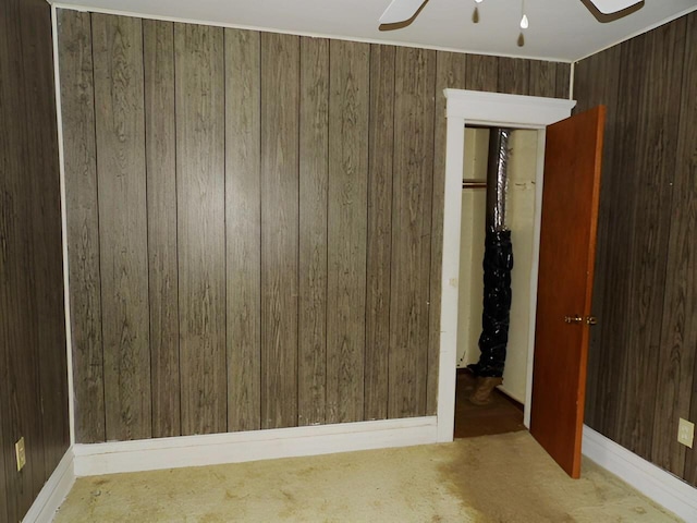 spare room featuring carpet, wood walls, and ceiling fan