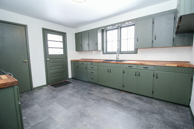 kitchen featuring green cabinets, butcher block counters, a sink, and a healthy amount of sunlight