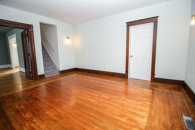 spare room with baseboards, visible vents, hardwood / wood-style floors, and stairs