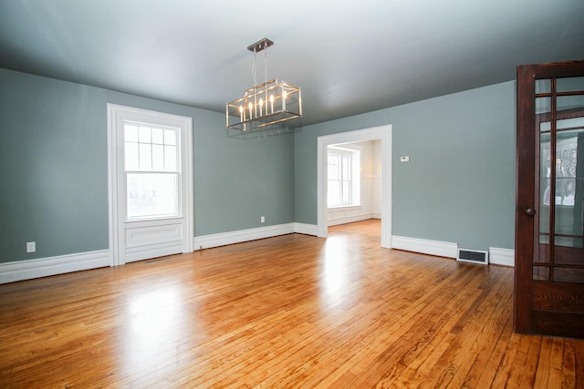 empty room with baseboards, visible vents, and hardwood / wood-style floors