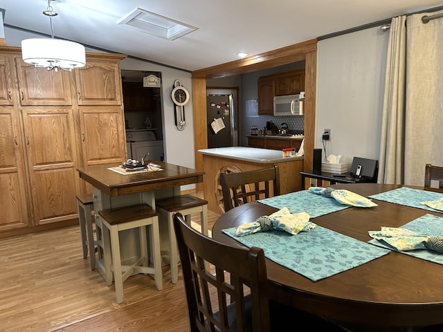 dining area with light wood-style floors, attic access, washer / clothes dryer, and vaulted ceiling