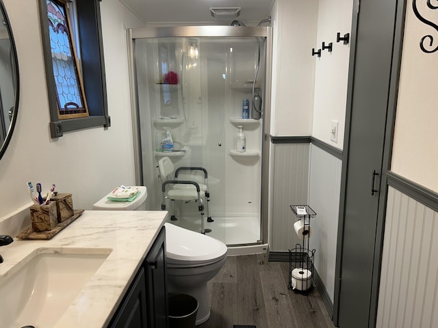 full bath with a stall shower, visible vents, wainscoting, toilet, and wood finished floors