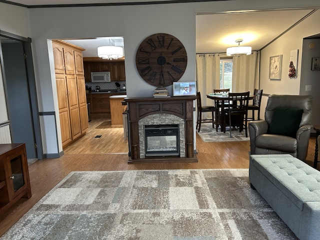 living area with ornamental molding, a chandelier, and light wood finished floors