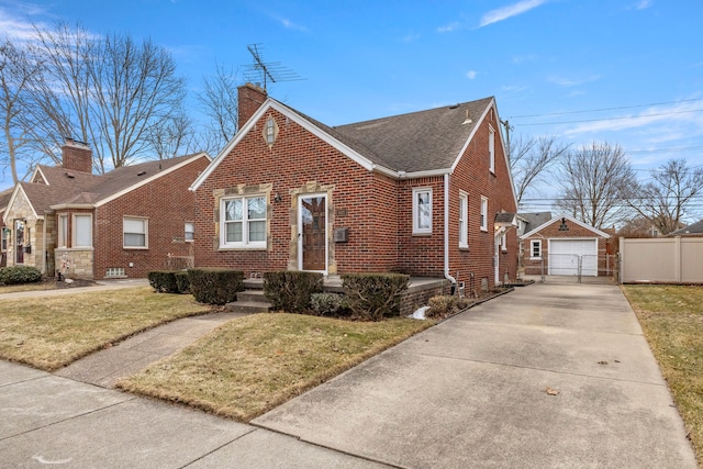 view of front of property with an outbuilding, brick siding, a detached garage, fence, and driveway