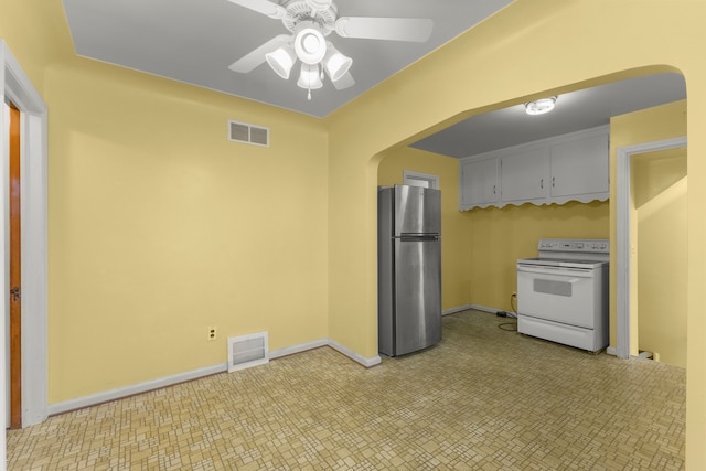 kitchen featuring visible vents, arched walkways, white range with electric cooktop, and freestanding refrigerator