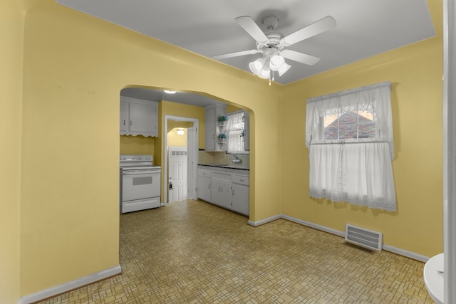 kitchen featuring baseboards, visible vents, arched walkways, and electric stove