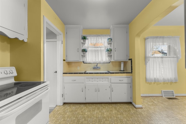 kitchen featuring tile countertops, open shelves, tasteful backsplash, visible vents, and electric range