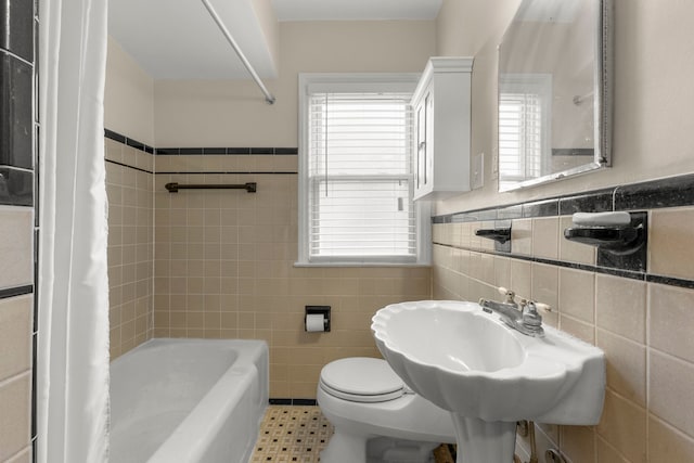 full bathroom with shower / tub combo, a healthy amount of sunlight, tile walls, and toilet