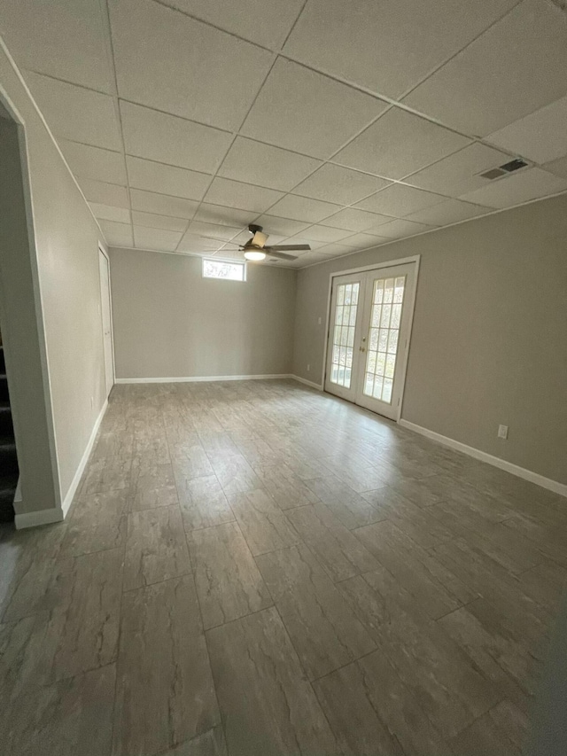 empty room featuring a paneled ceiling, stairway, visible vents, and baseboards