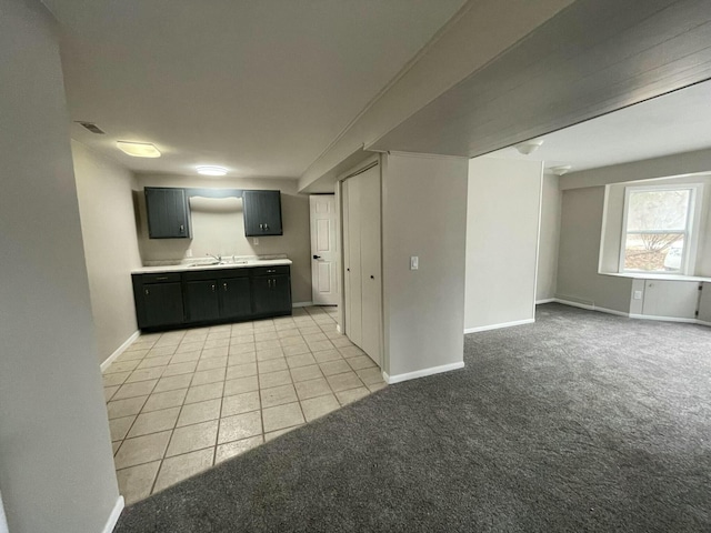 interior space featuring light tile patterned floors, baseboards, a sink, and light colored carpet