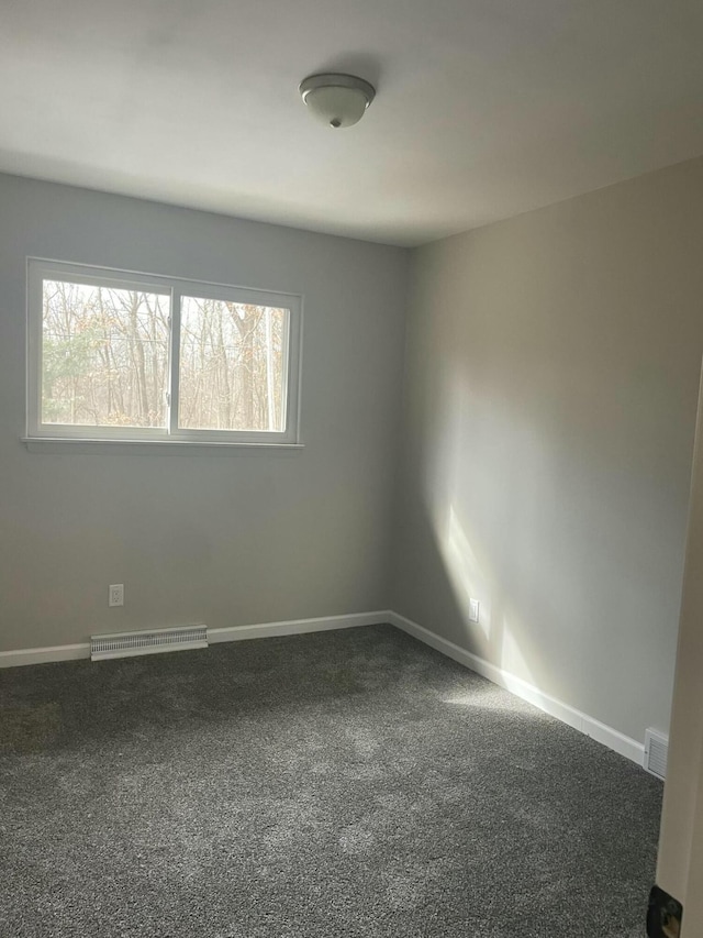 empty room with carpet floors, visible vents, and baseboards