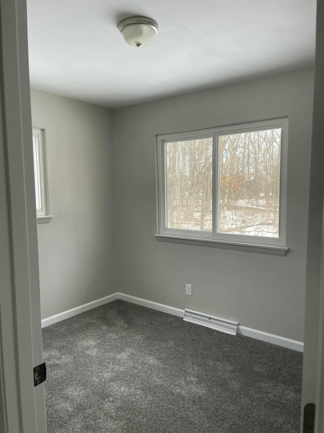 empty room with baseboards, visible vents, and dark carpet