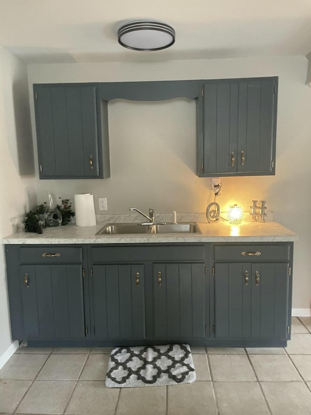 kitchen with light tile patterned floors, light countertops, a sink, and baseboards