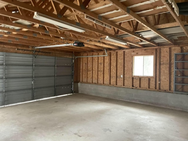 garage featuring concrete block wall and a garage door opener