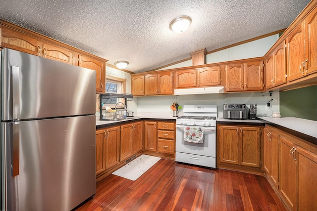 kitchen featuring brown cabinets, lofted ceiling, freestanding refrigerator, white range with gas stovetop, and under cabinet range hood