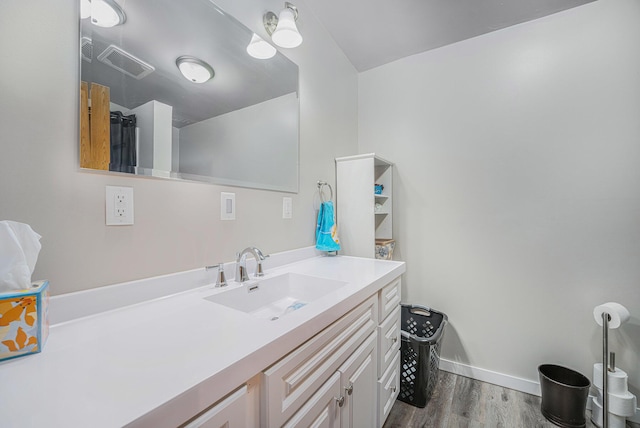 bathroom featuring baseboards, visible vents, wood finished floors, and vanity