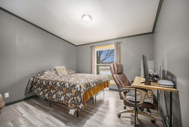 bedroom with ornamental molding, wood finished floors, and baseboards