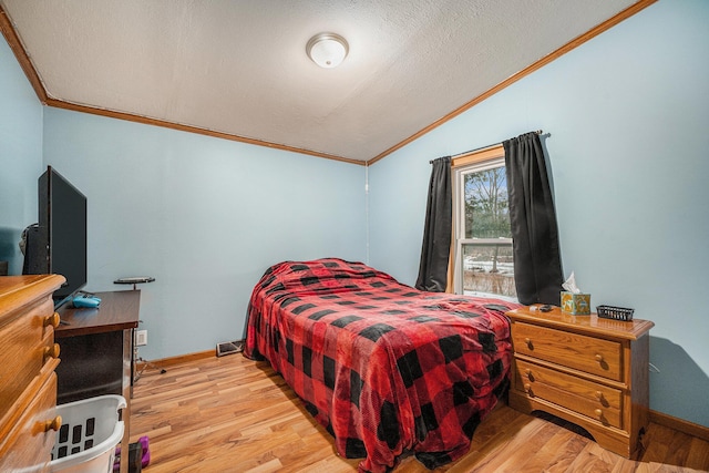 bedroom with a textured ceiling, visible vents, vaulted ceiling, light wood finished floors, and crown molding