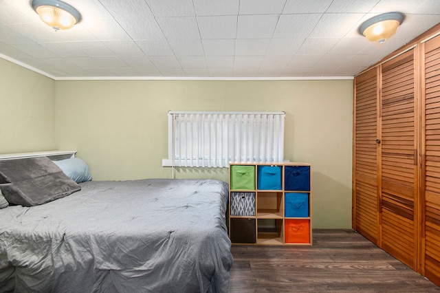 bedroom with ornamental molding, a closet, and wood finished floors