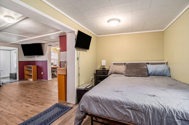 bedroom with ornamental molding and wood finished floors