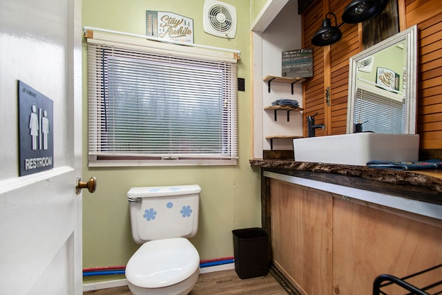 half bathroom with visible vents, toilet, vanity, wood finished floors, and baseboards