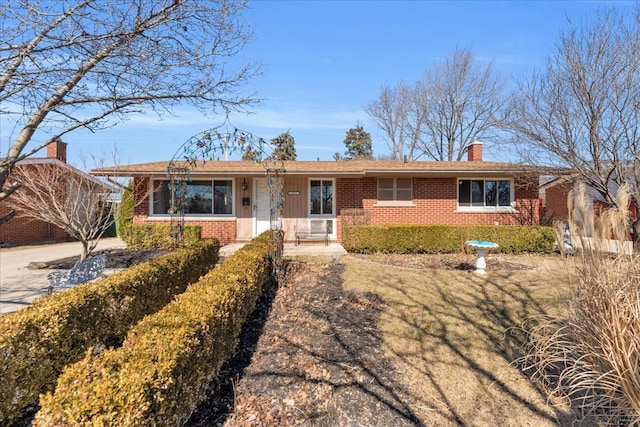 single story home with brick siding and a chimney