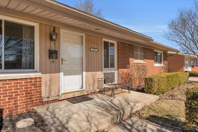 view of exterior entry featuring covered porch and brick siding