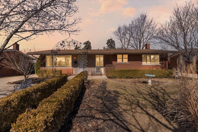 ranch-style home featuring brick siding and a chimney