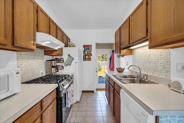 kitchen featuring under cabinet range hood, a sink, white appliances, light countertops, and light tile patterned floors