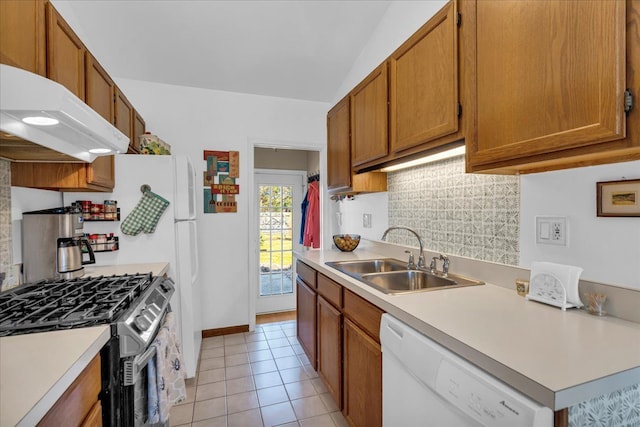 kitchen with backsplash, under cabinet range hood, stainless steel range with gas stovetop, white dishwasher, and a sink