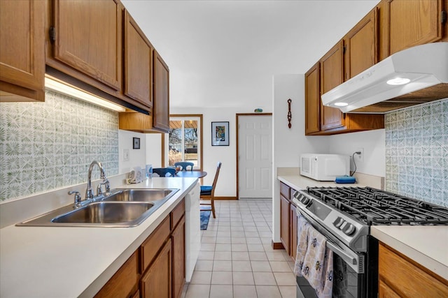 kitchen featuring under cabinet range hood, a sink, white appliances, light countertops, and light tile patterned floors