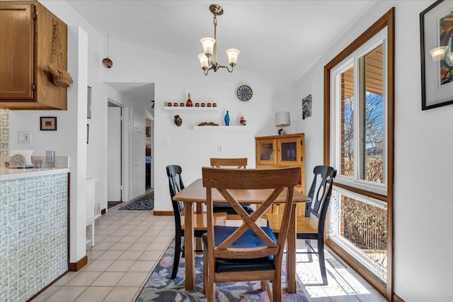 dining space with vaulted ceiling, a notable chandelier, light tile patterned floors, and baseboards