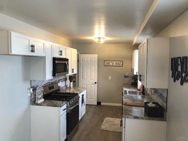 kitchen featuring stainless steel appliances, tasteful backsplash, dark wood-type flooring, a sink, and baseboards