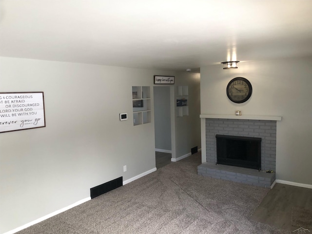 unfurnished living room with a brick fireplace, carpet flooring, and baseboards