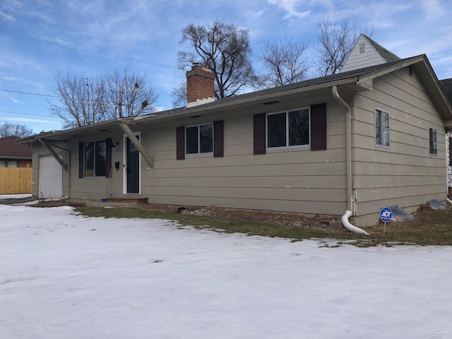 single story home with a chimney, an attached garage, and fence