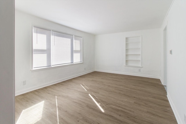 225 E Home St, Edmore, MI 48829 - empty room featuring built in features, wood finished floors, and baseboards