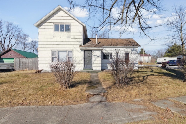 view of front of home featuring a shingled roof, fence, and a front yard