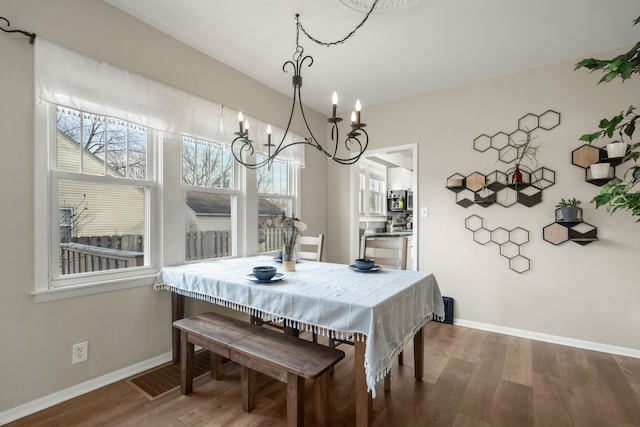 dining room featuring a chandelier, wood finished floors, and baseboards