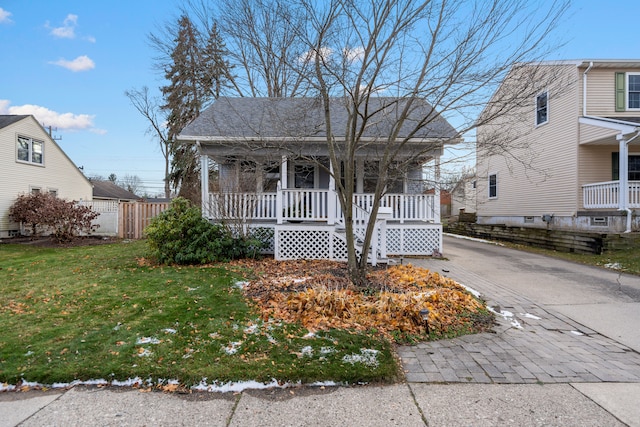 view of front of house with a porch, a front lawn, fence, and aphalt driveway