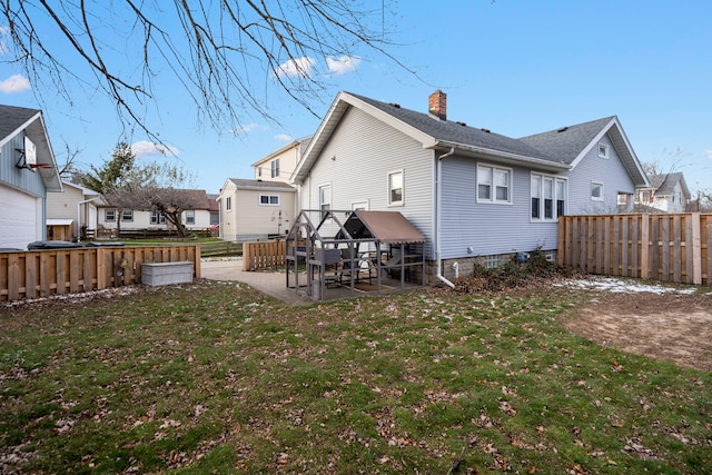 rear view of property with a yard, a fenced backyard, a chimney, and a patio