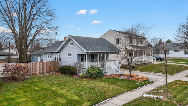 view of front of property featuring covered porch, a chimney, fence, and a front lawn