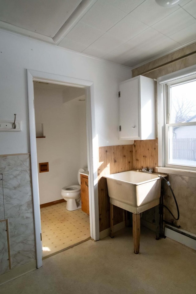 bathroom with toilet, a baseboard radiator, and wooden walls