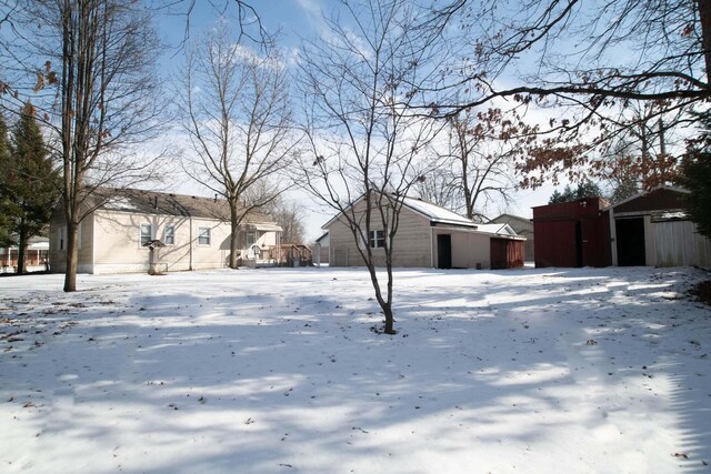 snowy yard with a garage and an outdoor structure