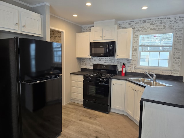 kitchen featuring light wood finished floors, dark countertops, white cabinets, a sink, and black appliances