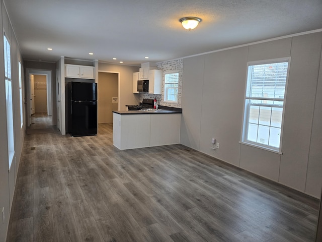 kitchen featuring black appliances, dark wood-style flooring, a peninsula, and white cabinets