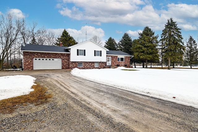 split level home featuring dirt driveway, brick siding, and an attached garage