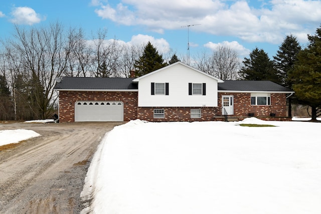 split level home featuring a garage, brick siding, driveway, crawl space, and a chimney